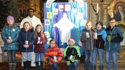 Kommunionkinder der Pfarrei Weidenthal mit Pfarrer Savari vor dem Kommunionplakat. (Bild: Ulrike Kiendl)