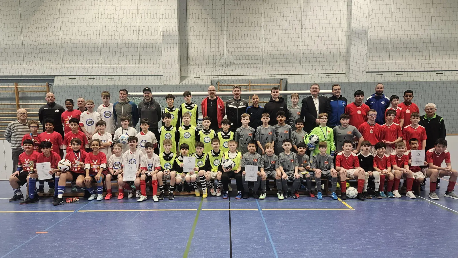 Die Jungen-Mannschaften nach der Hallen-Fußball-Landkreismeisterschaft der 5. und 6. Klassen von links: 1. MS Vilseck, 2. Realschule Auerbach, 3. MS Kümmersbruck I, 4. MS Kümmersbruck II und 5. Krötensee-MS mit (hinten, von links) Alexander Rittner (Betreuer Vilseck), Schiedsrichter Reinhard Wiesmeth, Sportlehrer Pavel Hes und Marco Mackenstein (beide RS Auerbach), Lehrer Matthias Brüchner, Rektor Florian Fuchs, Maresa Fuchs und Nicolai Fuchs (alle MS Kümmersbruck), 1. Bürgermeister Hans-Martin Schertl, Fußball-Obmann Alexander Merkl (Lehrer an der Mittelschule Kümmersbruck), Lehrer Maximilian Dietrich (Krötensee-MS) sowie Schiedsrichter Christian Trummer (Mitte, rechts) und (Mitte, links) Karl Heinz Grollmisch (Organisator vor Ort). (Bild: Karl Heinz Grollmisch)