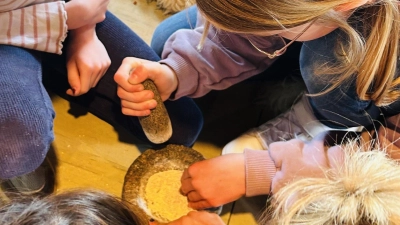 Die Kinder probierten es aus, mit steinzeitlichen Mitteln Getreide zu mahlen. (Bild: Ann-Kathrin Förderreuther/exb)