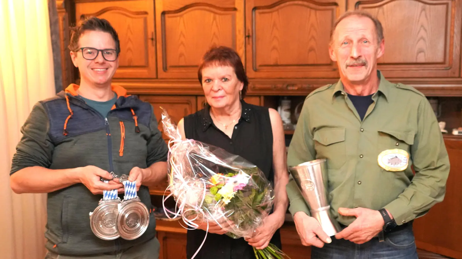 Kevin Bäumler (links) ist Vereinsmeister des Waldthurner Fischerstammtischs. Stammtischvorsitzender Wolfgang Fröhlich (rechts) dankt Hausherrin Christa Frank.<br>Fröhlich übergibt für den verhinderten Waldthurner Fischerkönig Herbert Bäumler den Pokal an dessen Sohn Kevin. (Bild: Franz Völkl)