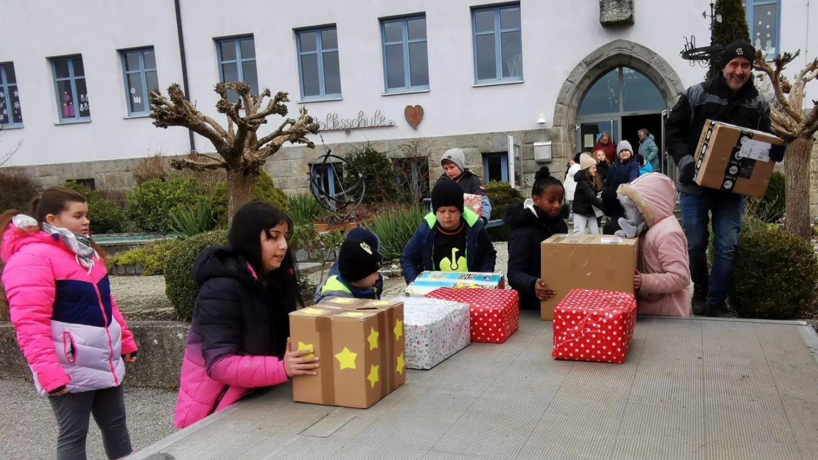 Die Schulkinder und Lehrerinnen helfen Luke Wüst beim Einladen der Weihnachtspakete. (Bild: Karl Ziegler)