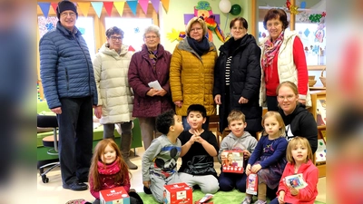 Die Kinder wussten genau, was Tonie-Boxen sind und wollten alles gleich auspacken. Kindergartenleiterin Theresa Schiller (vorne, rechts, knieend) und Pfarrer Berthold Heller (links) freuten sich über die Geschenke, die FU-Vorsitzende Renate Müller (Dritte von rechts) und ihre Vorstandsdamen mitgebracht hatten. (Bild: wlr)