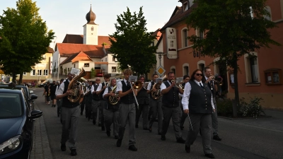 Das Orchester marschiert über den Marktplatz, im Hintergrund die Pfarrkirche St. Georg Schlicht.  (Bild: Lena Wiesnet)