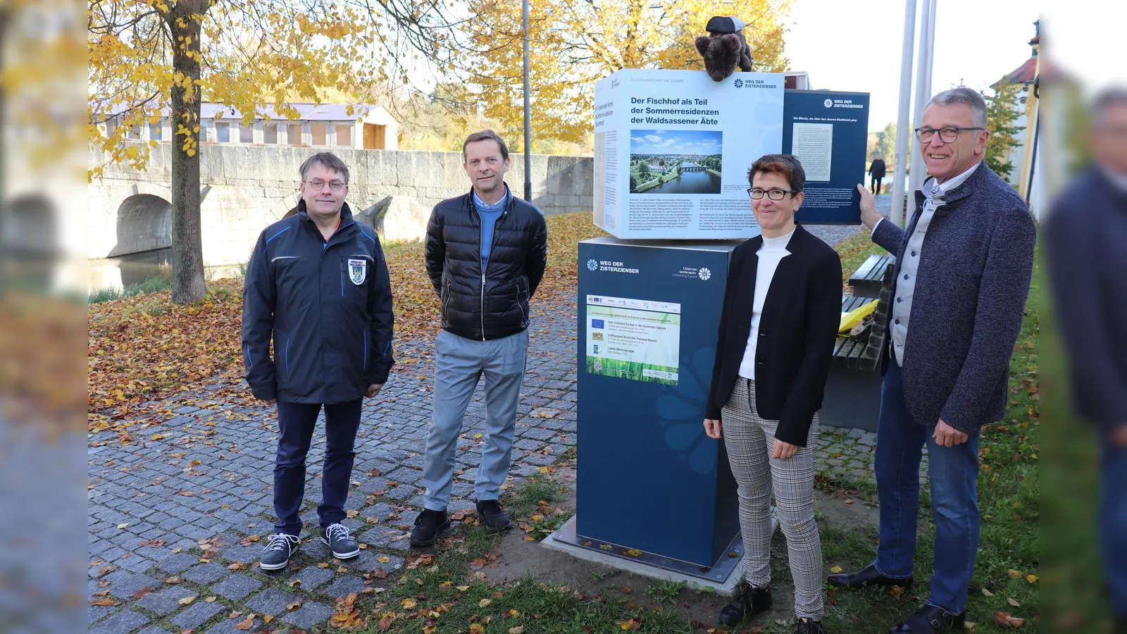 Bürgermeister Franz Stahl mit Martina Zanner, dem Leiter der Hauptverwaltung Markus Bergauer und Bauhofleiter Reinhard Legat (von rechts) bei der Präsentation der Infostation. Verfolgt wird diese vom auf der Station liegenden Zisterzienserweg-Maskottchen Berni, einem Wildschwein. (Bild: Stadt Tirschenreuth/exb)