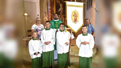 bei der Präsentation der restaurtierten Jugendfahne: (hinten) Mesnerin Elisabeth Dürgner, Pfarrvikar Yeruva und Kirchenpfleger Peter Falk; (vorne) diensthabende Ministranten bei der Sonntagsmesse (Bild: Norbert Weis)