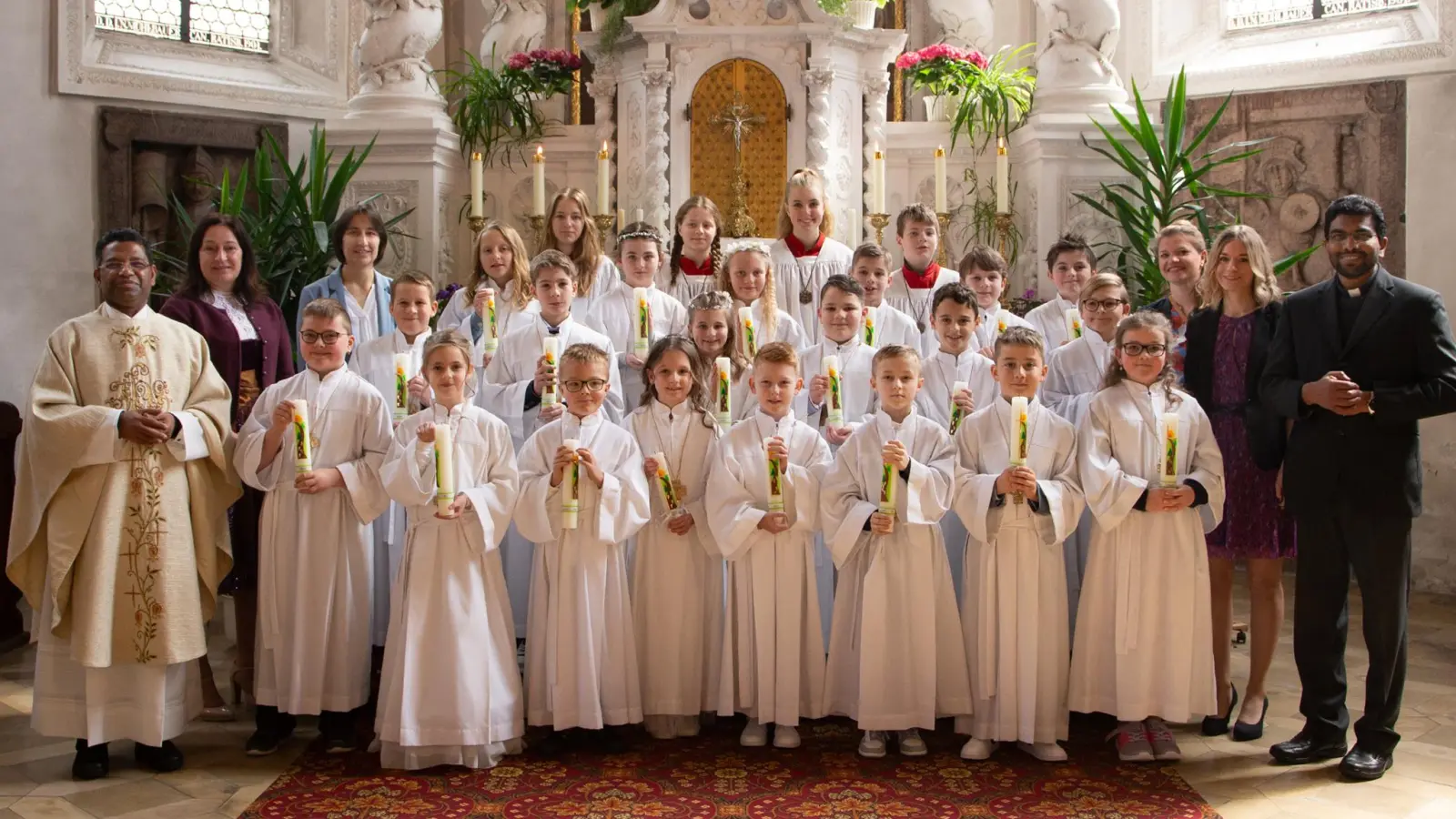 20 Erstkommunionkinder zusammen mit Pfarrer P. Georg Parmampilthadathil, der Rektorin Silke Schmid, der Religionslehrerin Reinhilde Bodensteiner, Pfarrvikar P. Joseph Vembadamthara, den Klassenlehrerinnen Kristina Pleier und Elisabeth Ertl sowie dem liturgischen Dienst.  (Bild: Sandra Dobmeier)