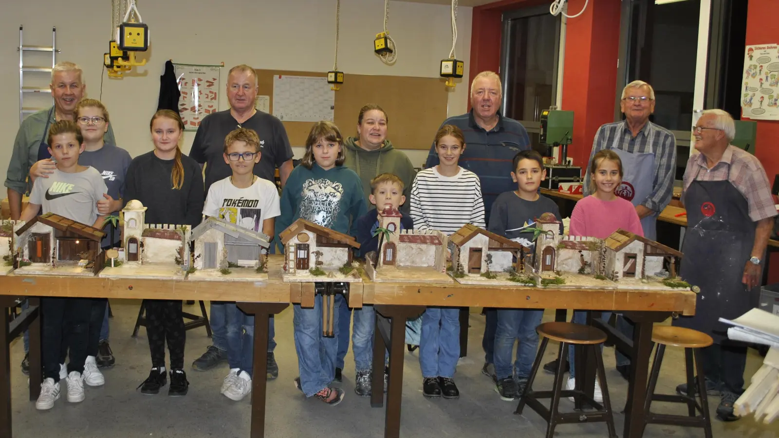 Voller Stolz präsentierten die Kinder am Ende des letzten Kursnachmittags ihre neuen Krippen. Mit auf dem Bild die Kursleiter und -helfer aus den Reihen des Krippenvereins, hinten v. r. Bernhard Büller, Peter Pichl, Richard Rauch, Manuela Fronhofer, Max Blank und Uli Reindl.  (Bild: Carolin Kausler )