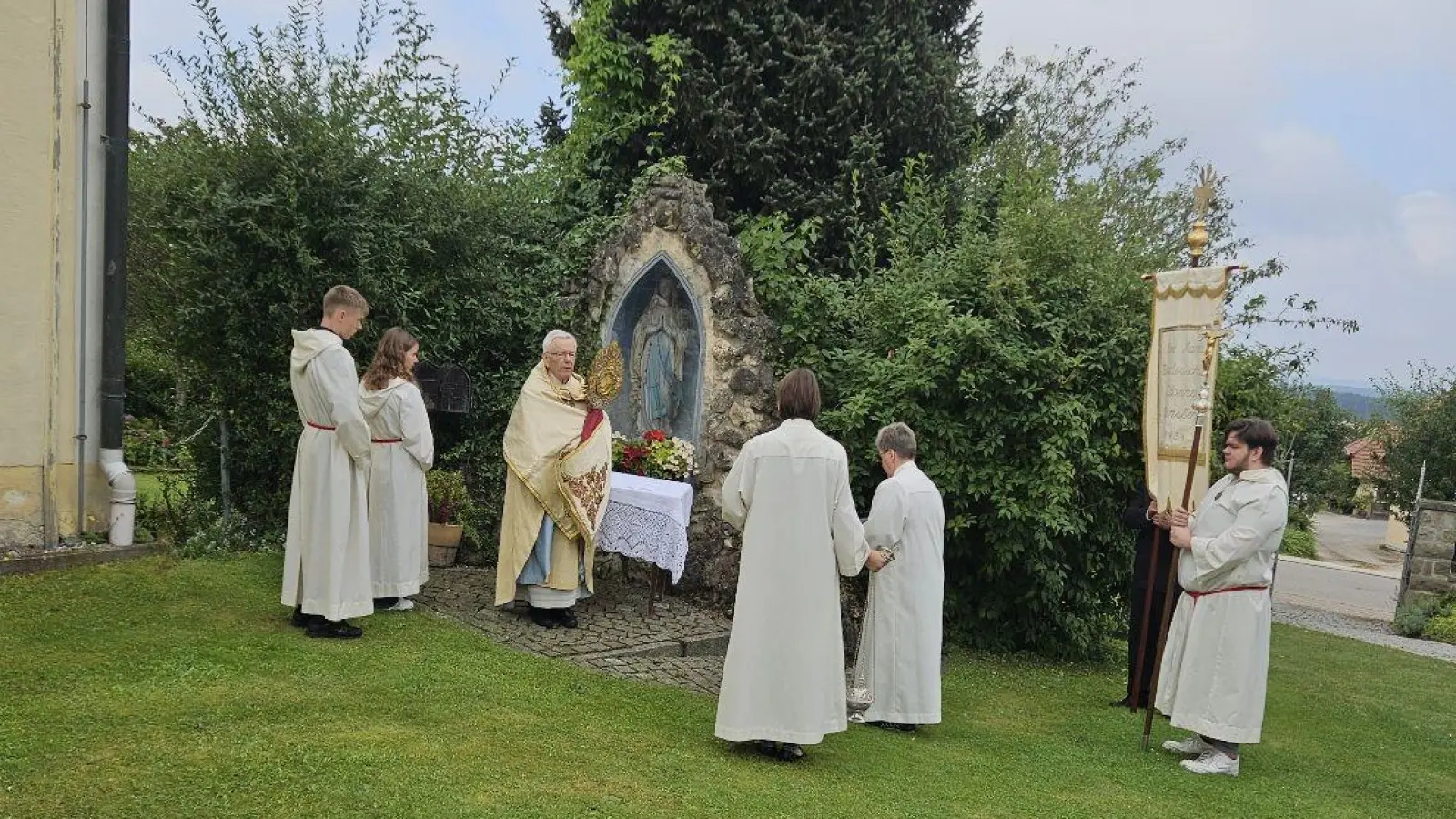 Pfarrer Josef Beer am Ende der gläubigen Feier vor der Pittersberger Lourdes-Grotte beim Eucharistischen Segen an die zahlreichen Bruderschaftsmitglieder, dazu Gästen, die von außerhalb der Nikolauspfarrei gekommen waren. (Bild: Michael Götz)