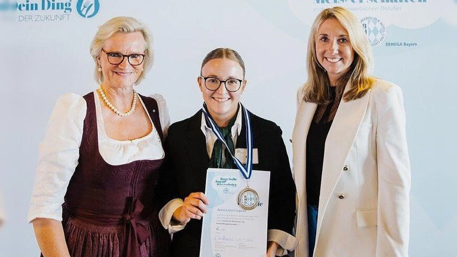 Anna-Lina Leupold mit Urkunde und Medaille des 2. Platzes. Es gratulierten DEHOGA-Vizepräsidentin Angela Inselkammer (links) und Kultusministerin Anna Stolz (rechts). (Bild: Inge Gebert)