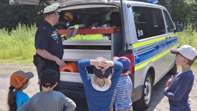 Polizeioberkommissar Carsten Landgraf von der Polizeiinspektion Kemnath zeigte den Kinder, was sich im Kofferraum eines Einsatzwagens befindet. (Bild: Waldkindergarten "Die Goldbacher Wurzelzwerge"/exb)