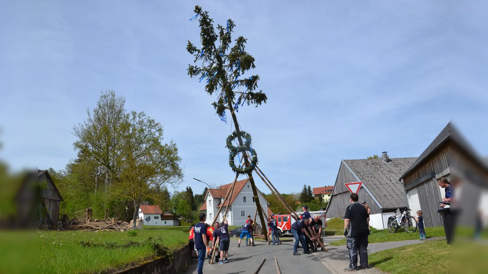 Die Feuerwehr Burgtreswitz stellt ihren Maibaum auf, der mit zwei Kränzen und blau-weißen Bändern geschmückt ist. (Bild: gi)