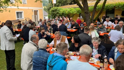 Pfarrer Emmanuel Okoro (stehend links) freute sich über den sehr guten Besuch beim Pfarrfest in Unterauerbach anlässlich des Weihetages der Kirche St. Nikolaus und dankte allen, die zum Gelingen beigetragen haben. (Bild: Franz Grabinger)