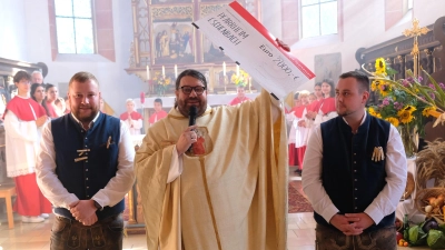 Stadtpfarrer Pater Johannes Bosco jubelt über eine großzügige Spende des Kirwavereins. Den symbolischen Scheck überreichten im feschen Vereins-Outfit Vorsitzender Philipp Gottsche (re) und sein Stellvertreter Sebastian Wohlrab (li).  (Bild: Robert Dotzauer)