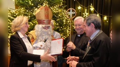  In Anwesenheit von St. Nikolaus und Pfarrer Wilfried Römischer überreichte Marlene Noetzel (links) an Pfarrer Max Früchtl (rechts) einen Gutschein über 500 Euro. (Bild: Fred Lehner)