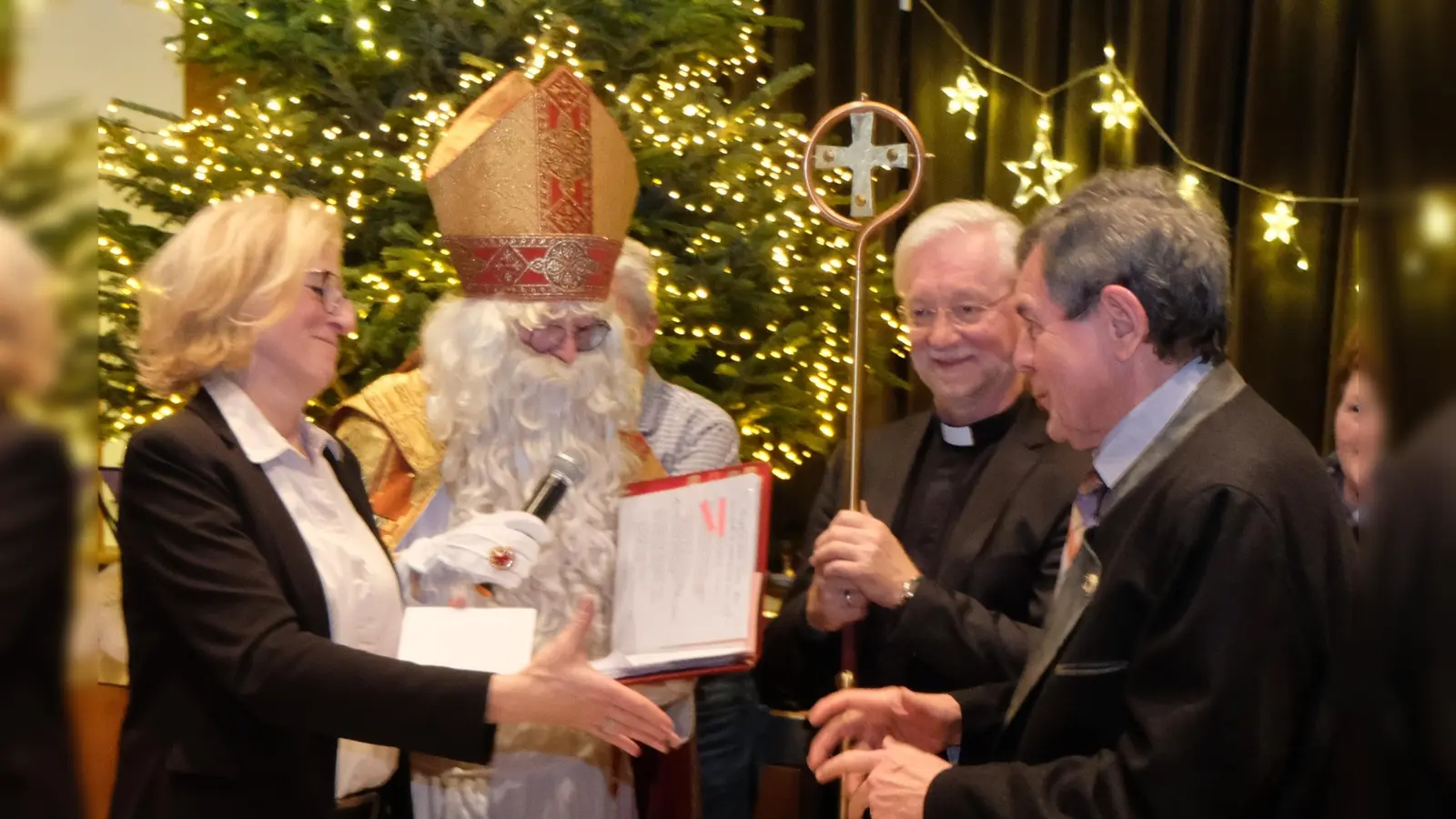  In Anwesenheit von St. Nikolaus und Pfarrer Wilfried Römischer überreichte Marlene Noetzel (links) an Pfarrer Max Früchtl (rechts) einen Gutschein über 500 Euro. (Bild: Fred Lehner)