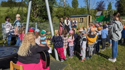 „Kinder, kommt vor, jetzt wird gleich das Band zum Spielbauwagen durchschnitten“ ruft Vroni Lehner auf der Bühne (2.v.links) inmitten weiterer Mitglieder des Elternbeirats. Auch Helfer Gregor (links mit Strohhut) ist mit Freude dabei. (Bild: Hans Eibauer)