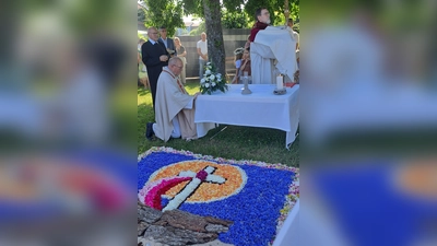 Diakon Franz-Josef Reck (mit der Monstranz) und Pater Edward Lipiec (kniend) beim Altar der Vereine. Der Blumenteppich vor dem Altar trug hier das Motto „Wir können den Wind nicht ändern, aber die Segel anders setzen“. (Bild: Sonja Müller)