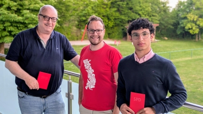 Vorsitzender Daniel Reichenberger begrüßt die beiden Neumitglieder Hinrich und Anwar Cordts und übergibt das rote Parteibuch (Bild: Norbert Mitlmeier)
