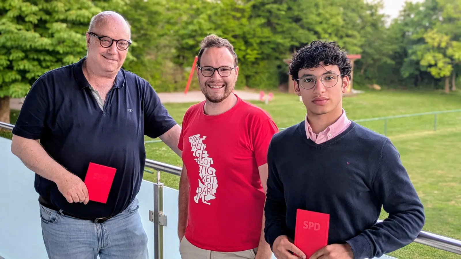 Vorsitzender Daniel Reichenberger begrüßt die beiden Neumitglieder Hinrich und Anwar Cordts und übergibt das rote Parteibuch (Bild: Norbert Mitlmeier)