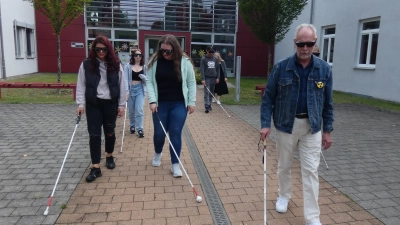 Die Schüler erkunden mit Brillen, die verschieden starke Sehbehinderungen simulieren, zusammen mit einem Blinden die Umgebung der Schule mit Langstöcken (Bild: Thomas Schiller)