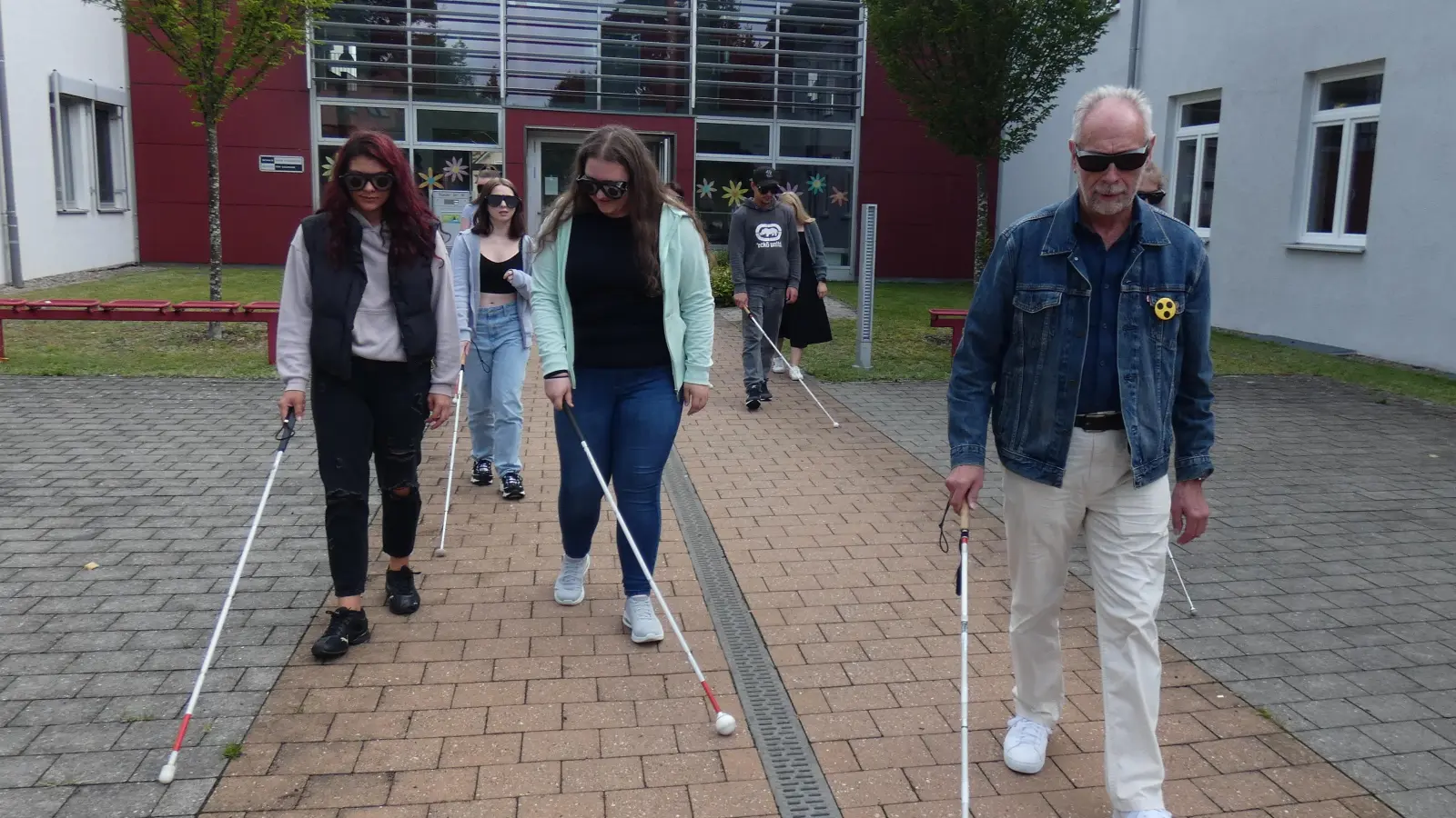 Die Schüler erkunden mit Brillen, die verschieden starke Sehbehinderungen simulieren, zusammen mit einem Blinden die Umgebung der Schule mit Langstöcken (Bild: Thomas Schiller)