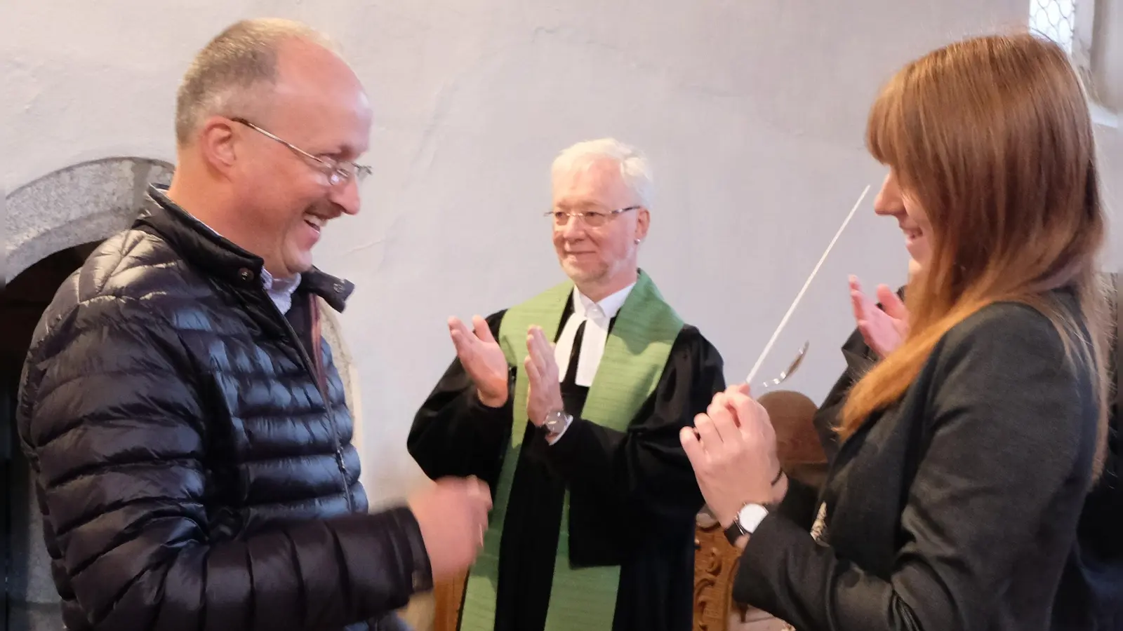 Offiziell übergab Wolfgang Lang (links) an seine Nachfolgerin Tanja Riedel (rechts) den Dirigentenstab worüber sich auch Pfarrer Römischer (Mitte) freute.  (Bild: le)