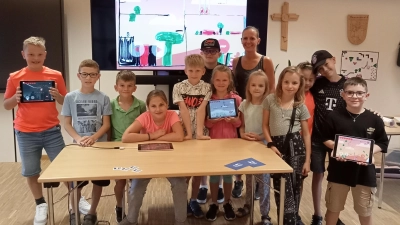 Auf dem Bild sind die teilnehmenden Kinder vom Ferienprogrammbeitrag „Game Designer“ mit ihren Videospielen sowie die Medienpädagogin Sabine Wagner vom T1 zu sehen. (Bild: Max Bindl)