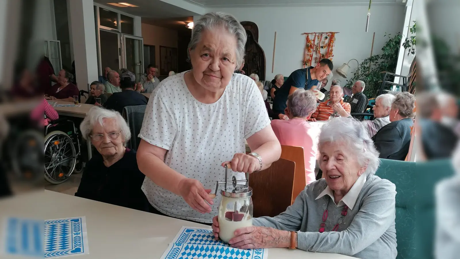 Bewohnerinnen rühren den Rahm im Butterfass (Bild: Sylvia Benjamin)