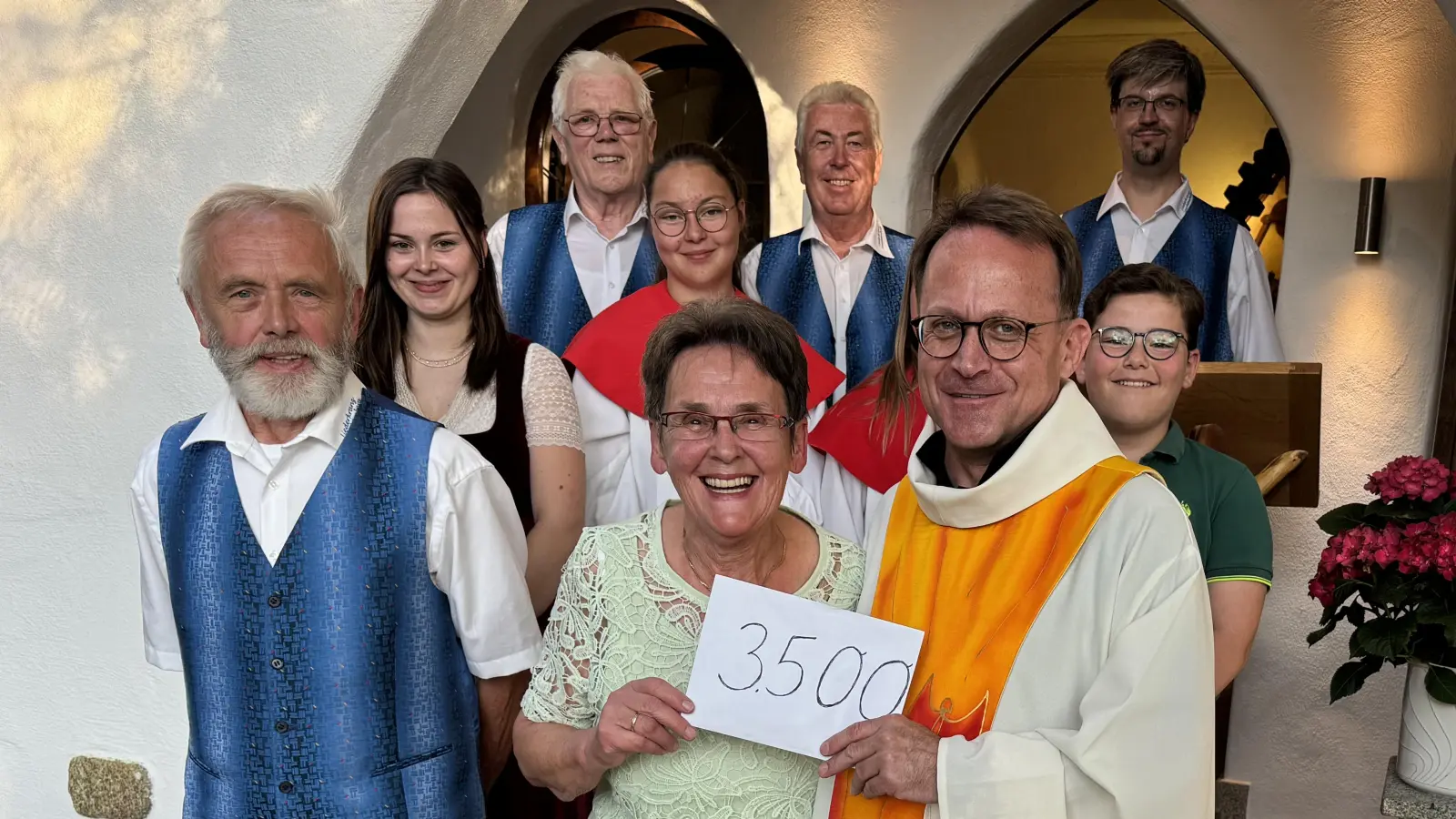 Christa Wildenauer steht die Freude ins Gesicht geschrieben, 3500 Euro an Dekan Alexander Hösl für die Kircheninnenrenovierung überreichen zu können. <br>Personen auf dem Foto: Ehepaar Christa und Helmut Wildenauer, Pfarrer Alexander Hösl, die Enkel Afra und Genoveva Fritz, Samuel Kreisl, einige Leuchtenberger Sänger (Bild: Alfons Raab)