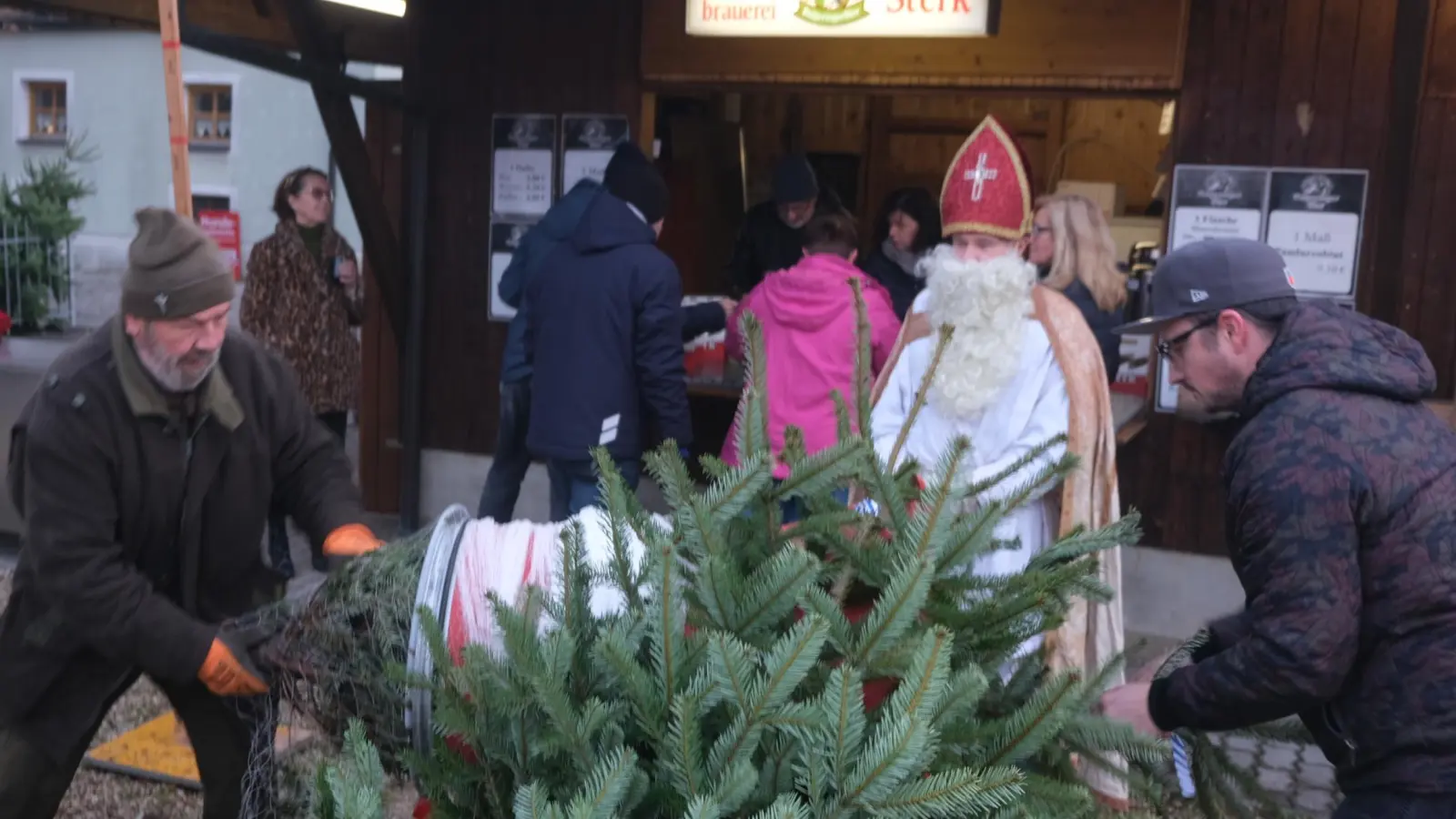 Bei Temperaturen über Null kamen die Christbaumverpacker vom Lions-Club Amberg-Sulzbach ganz schön ins Schwitzen. Da hatte es der Club-Nikolaus schon einfacher. (Bild: Hubert Uschald)