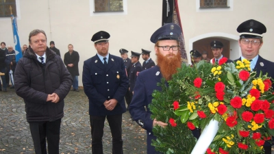 Anlässlich des Volkstrauertages legt Bürgermeister Gerhard Kellner (links) zusammen mit der Feuerwehr am Kriegerdenkmal einen Kranz nieder. Dieser soll Gedenken, Mahnung und Erinnerung zugleich sein. (Bild: sm)