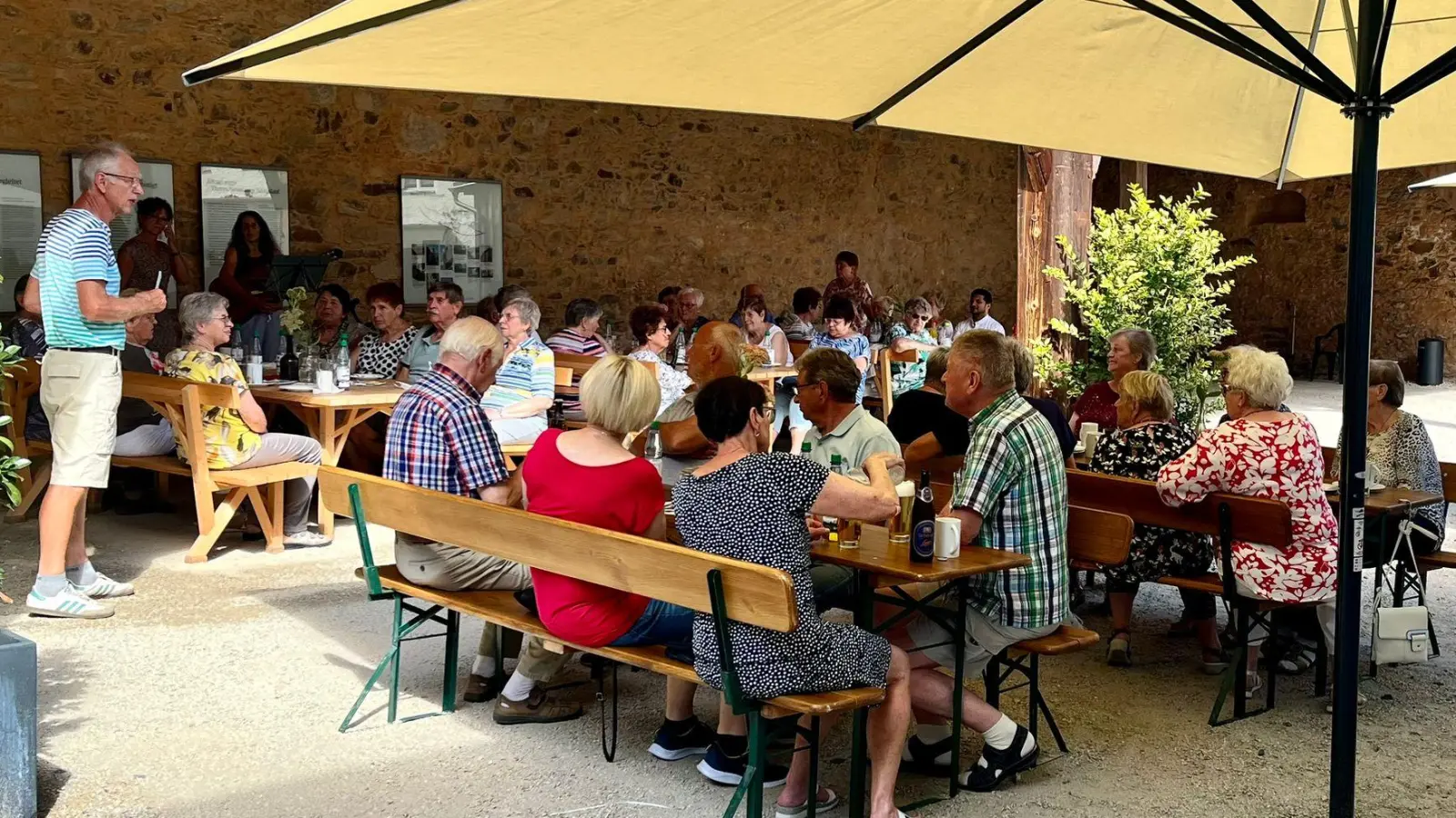 Seniorenbeauftragter Konrad Härtl ( links stehend ) mit einem Teil der Gäste unter der Remise im Schafferhof (Bild: Ulrike Sammet)