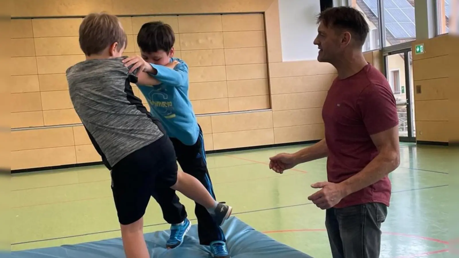 Zwei Buben der Grundschule lernen spielerisch unter Anleitung von Lorenz Gatzhammer, sich zu verteidigen, ohne wirklich Gewalt anzuwenden. Es geht um Geschicklichkeit und Mut, die Kinder erfahren ihre eigenen Möglichkeiten, mit klaren Ansagen und körperlicher Geschicklichkeit Meinungsverschiedenheiten friedlich und respektvoll zu klären.  (Bild: Christine Wendl)