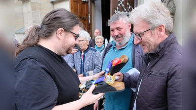 Zu den praktischen Geburtstagsgeschenken für den Eschenbacher und Kirchenthumbacher Pfarrherrn gehörten „Verwöhnschlappen” und bunte Wollsocken, gestrickt von besorgten „Schäfchen” der Pfarreiengemeinschaft und überreicht von den Kirchenpflegern Norbert Braun (re) und Josef Schreglmann (2.v.re.) (Bild: Robert Dotzauer)