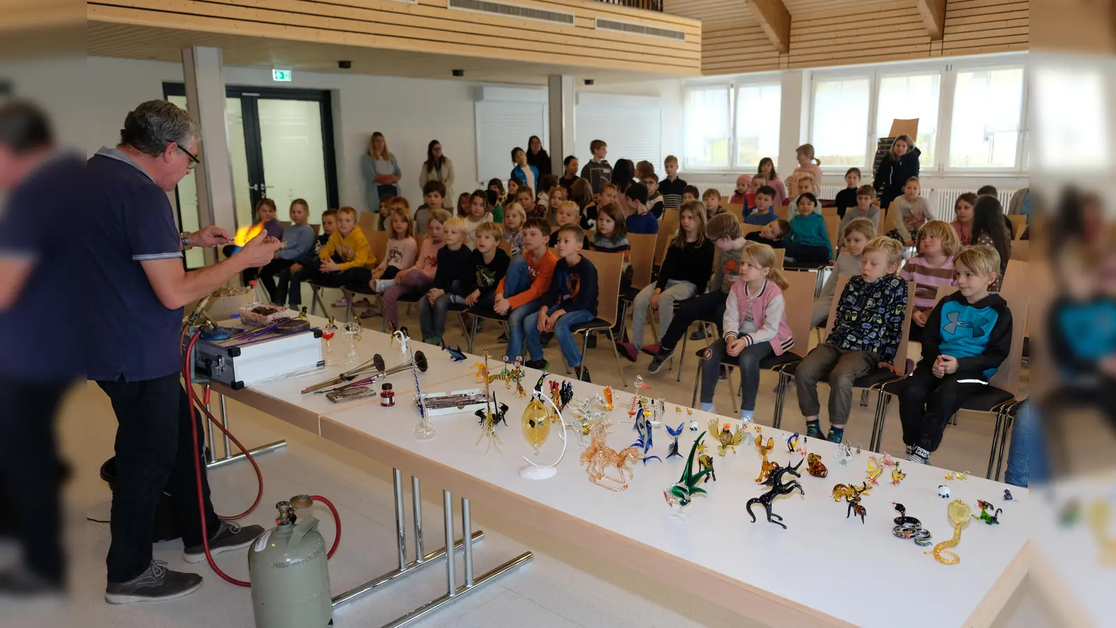 Anschaulich erfahren die Kinder der Grundschule am Rauhen Kulm beim Besuch des Coburger Glasbläsers Jürgen Piller, wie aus Rohglas mit viel Geschick und Können kleine Kunstwerke entstehen. (Bild: do)