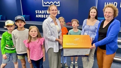 Stadtwerke Amberg-Auszubildende und Projektleiterinnen Elena Lasser und Lucy Söder übergeben ihre individuell, selbstgestaltete Windkraftkiste der DigiMINTkids e. V. Vorsitzende Brigitte Netta. Die Kinder Anna Diekmann, Theresa Echinger, Adam Dehling, Jan Daiker und Paul Dehling hatten bereits das Vergnügen das neue Windkraftmaterial auszuprobieren.  (Bild: Karoline Gajeck-Scheuck)