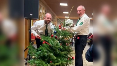 1. Schützenmeister Andreas Hammer (links) sowie der Schießleiter und zugleich Böllermeister Herbert Raß (rechts) haben da gegen Ende der Christbaumversteigerung beim Absägen des Gipfels schon gut lachen, denn der Abend war letztlich für die Bergschützen ein voller Erfolg! (Bild: Michael Götz)