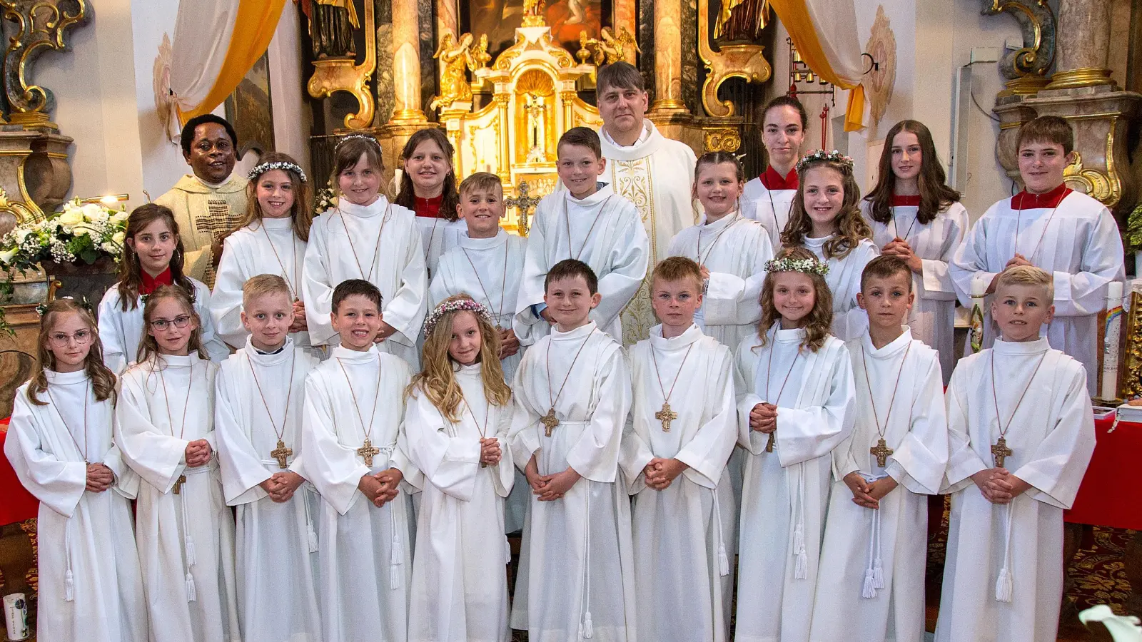 Bei schönstem Wetter wurde in Rottendorf Erstkommunion gefeiert. Die Kinder der dritten Klasse stellten sich zusammen mit Pfarrer Oliver Pollinger, der als Patenonkel eines Erstkommunionkindes die Feier zelebrierte und Kaplan Edmund Onah und den Ministranten zum Erinnerungsbild auf.  (Bild: Judith Deichl)