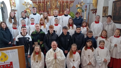 Pfarrer Heribert Stretz (vorne, Zweiter von links), die Ministranten-Betreuerinnen Angelika Kaufmann (dritte Reihe, links) und Irmi Schmidt (dritte Reihe, rechts) sowie Pfarrgemeinderatssprecherin Elisabeth Merkl (hinten links) hießen die neuen „Minis“ willkommen und verabschiedeten langjährige Altardiener. (Bild: Birgit Übelmesser/exb)