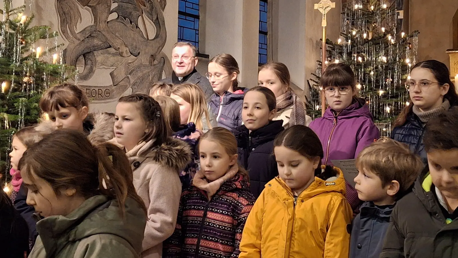 Regionaldekan Markus Brunner bei seiner Begrüßung zum Konzert zum Abschluss der Weihnachtszeit in St. Barbara. Umgeben von den Kindern des Kinder- und Jugenchors St. Michael Poppenricht (Bild: Christian Beck)