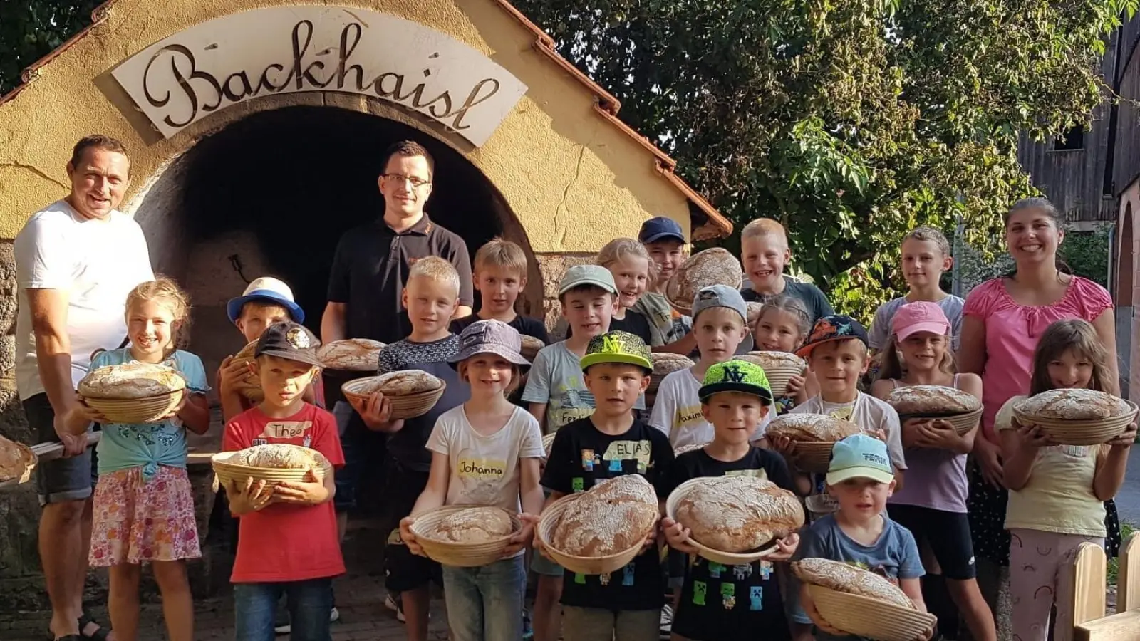 Feuerwehrkommandant Rudi Schinner (hinten, links) freut sich zusammen mit seiner Frau Daniela (hinten, rechts), seinem Stellvertreter Manuel Köllner (hinten, Mitte) und den Kindern über die gelungene Brotbackaktion. (Bild: Heidi Banzer)