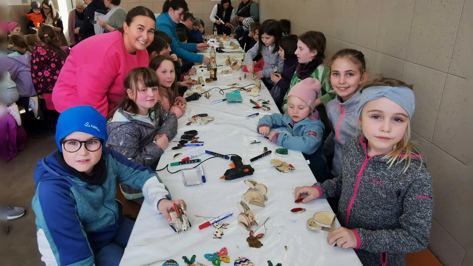 Jugendbeauftragte Laura Roth zeigt den Kindern, wie aus Birkenscheiben kleine Holz-Osterhasen werden. (Bild: gz)