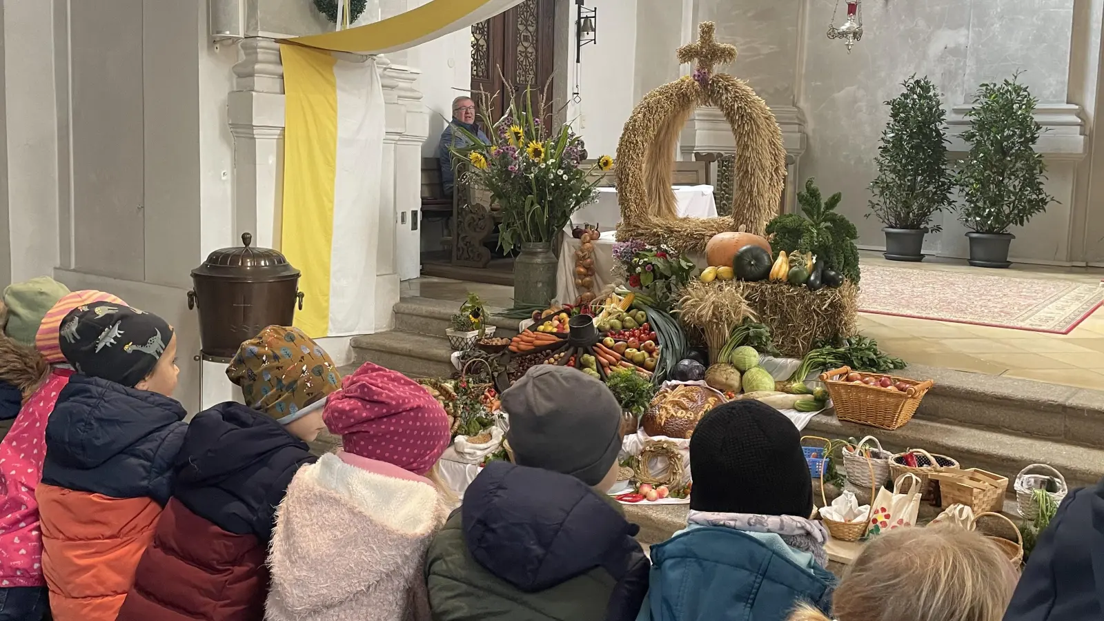 Die Jungen und Mädchen des Kinderhauses St. Marien blickend auf die Erntedankkrone. (Bild: Carolin Ernstberger)