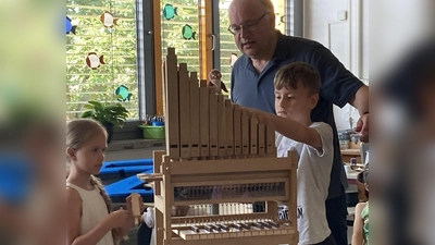 Organist Bernhard Müllers mit zwei Schülern beim Erforschen der kleinen Orgel. (Bild: Michaela Meier/exb)