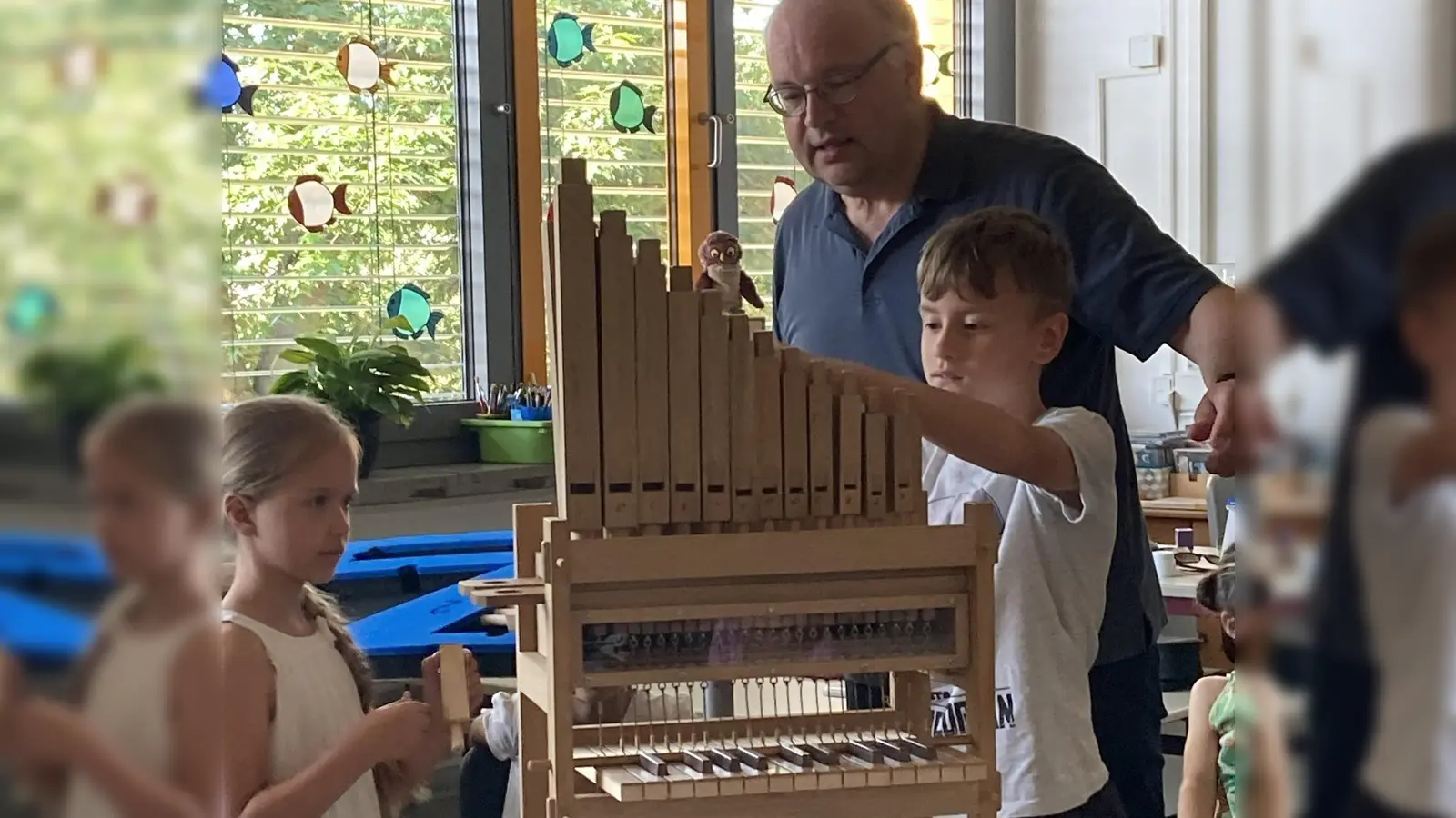 Organist Bernhard Müllers mit zwei Schülern beim Erforschen der kleinen Orgel. (Bild: Michaela Meier/exb)