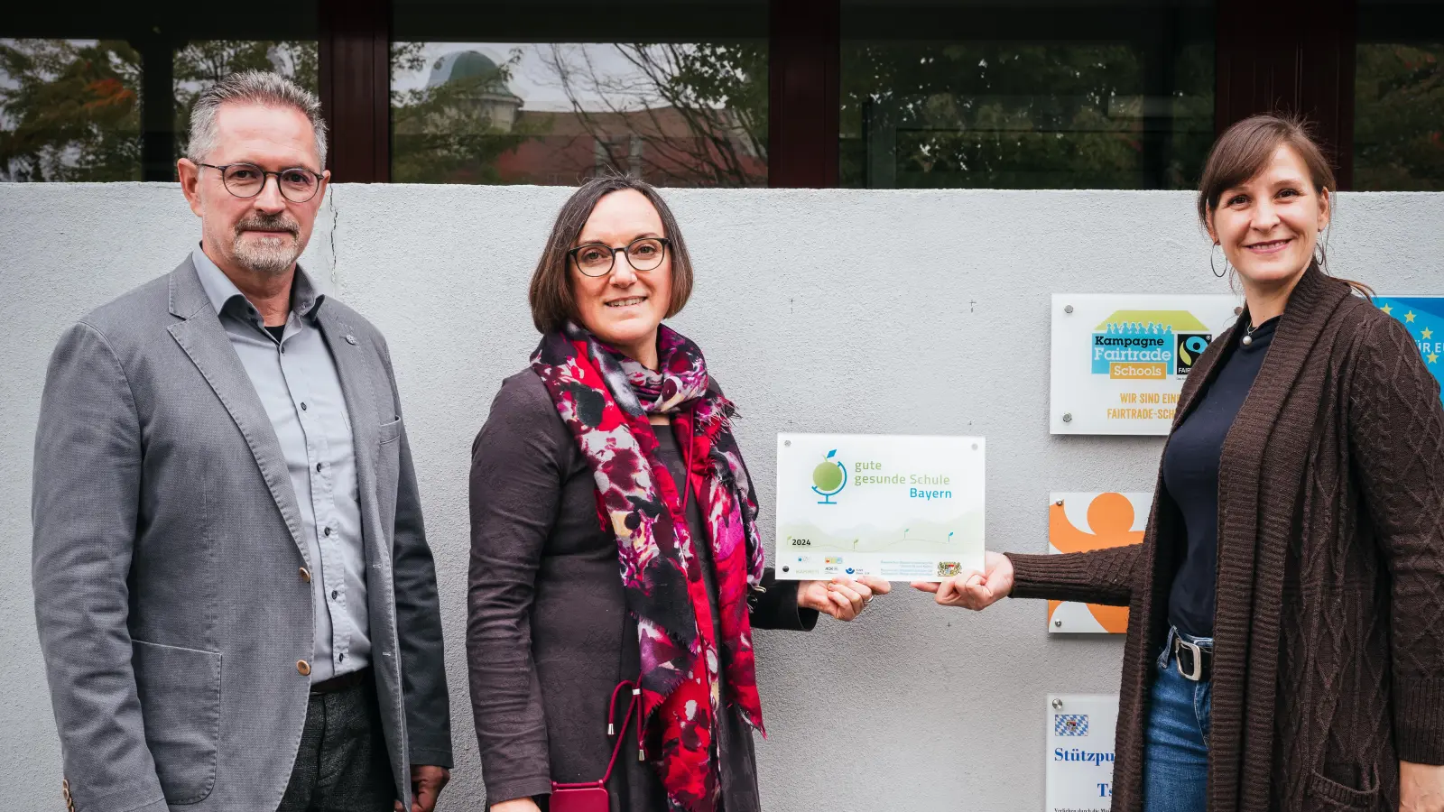 RSD Stephan Drexler zusammen mit den Lehrkräften FOLin Birgit Plößner und StRin Barbara Strenge beim Anbringen der neuen Auszeichnung „Gute und gesunde Schule Bayern” (Bild: Tobi Frauendorfer)