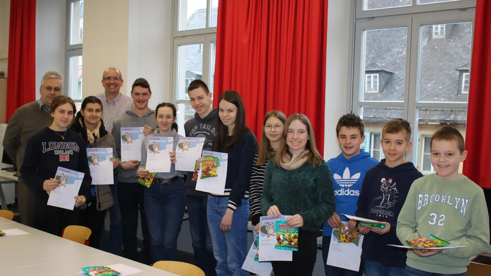 Das Bild zeigt die erfolgreichen Schülerinnen und Schüler aus verschiedenen Jahrgangsstufen zusammen mit Schulleiter Joachim Zembsch (hinten links) neben IT-Lehrer Stefan Landgraf im Computerraum des Luisenburg-Gymnasiums bei der Übergabe der Urkunden und Preise. (Bild: Markus Wagner)