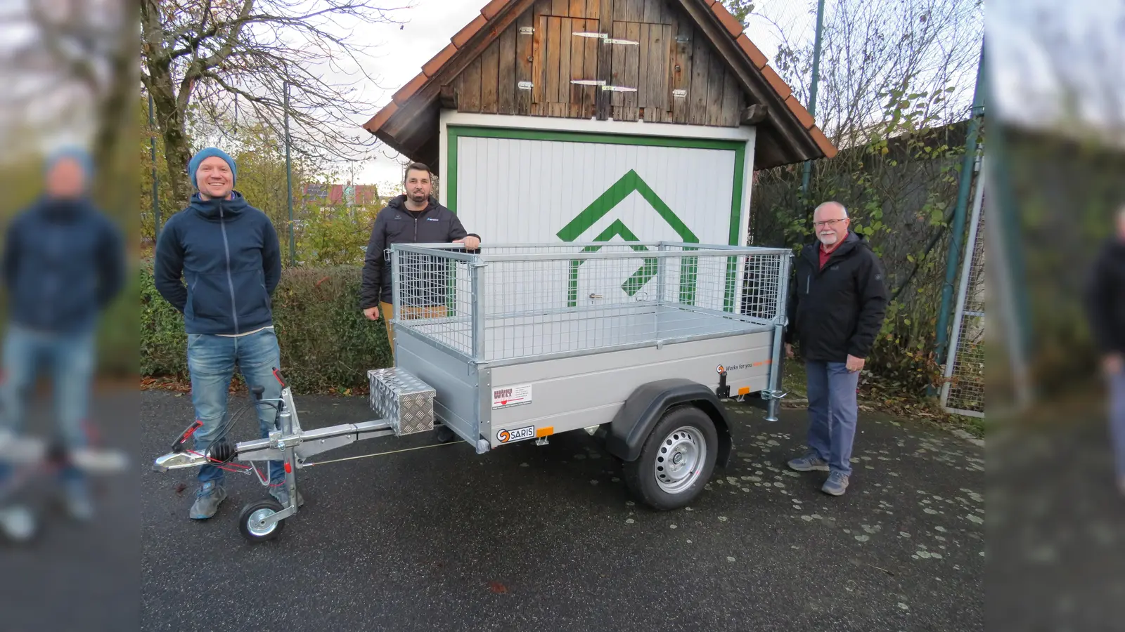 Den neuen Anhänger präsentierten Gerrit Kreuzer (Künstler der Garagentorgrafik und Kassier), Manuel Gössl (1. Vorstand), Klaus Leipold (Gerätewart) vor der mit neuen Logo gestalteten Garage. (Bild: adj)