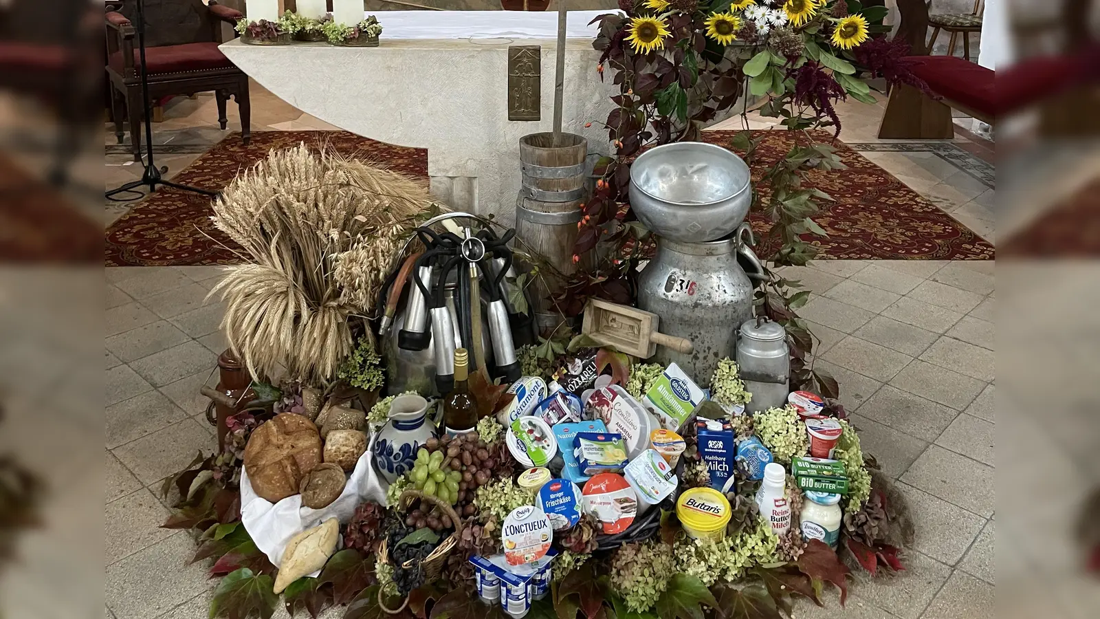 Der reichhaltige Gabenaltar zum Thema Milch des Jahres 2024 in der Pittersberger Nikolauskirche der Jetzt-Zeit, angefangen von den Lebensmittel-Erzeugnissen der heutigen Zeit bis hin zum modernen Melkgeschirr oder auch dem Butterfassl von früher.  (Bild: Michael Götz)