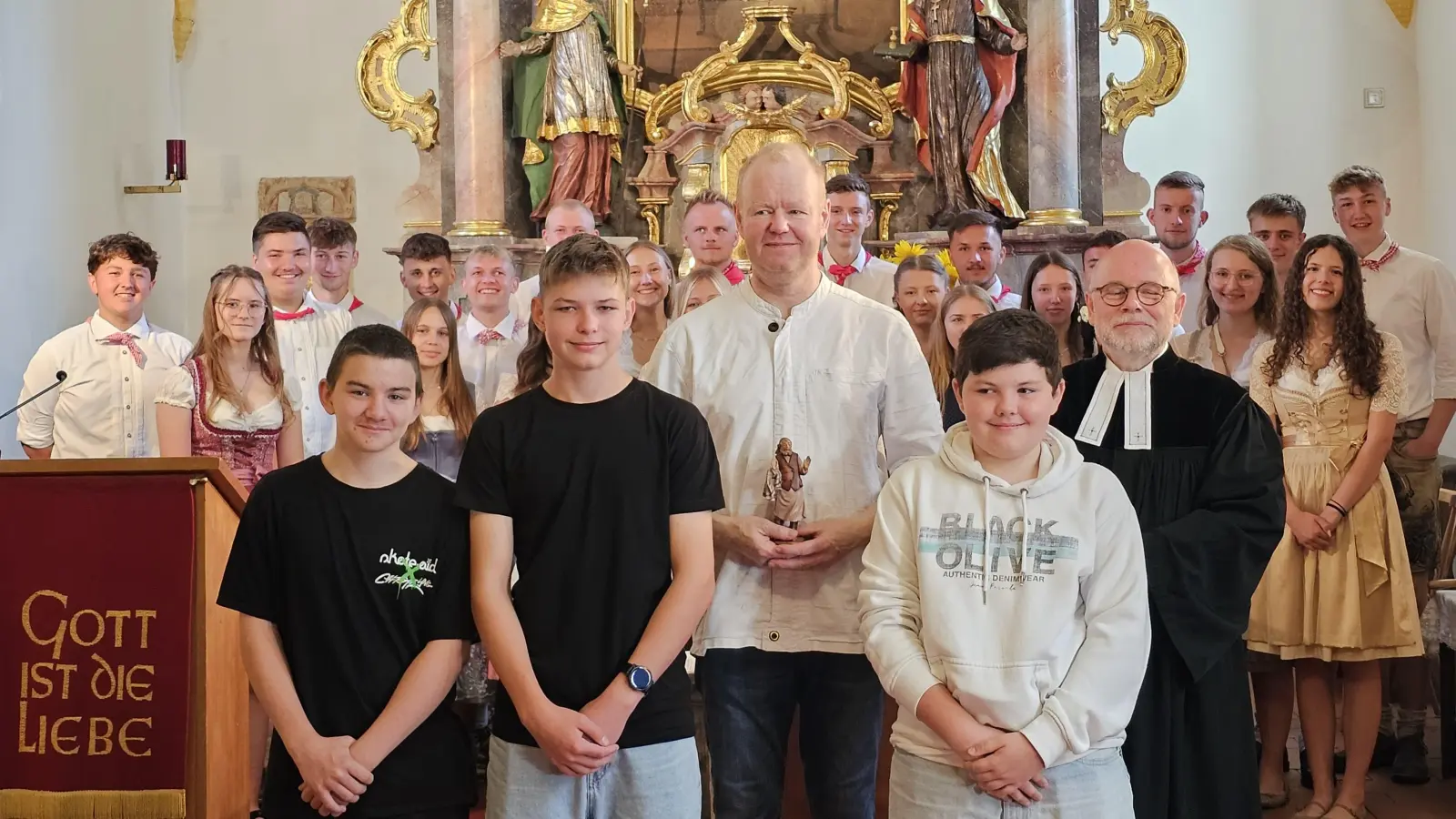 Die drei Konfirmanden Leon, Louis und Luca übergaben dem Wirt Marko Spieß (3. von links) ihre gespendete Figur des Wirtes für die Krippe der Kürmreuther Kirche. Pfarrer Matthias Ahnert leitete diesen Kirchweihgottesdienst, den die 12 Kirchweihpaare besuchten.  (Bild: Heidi Kurz)